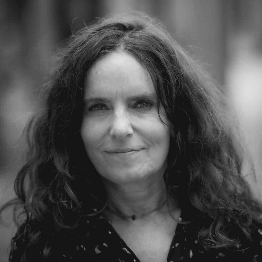 Portrætbillede af en kvinde fra Center for Autisme med langt, mørkt, krøllet hår. Hun ser roligt ind i kameraet med et venligt udtryk.