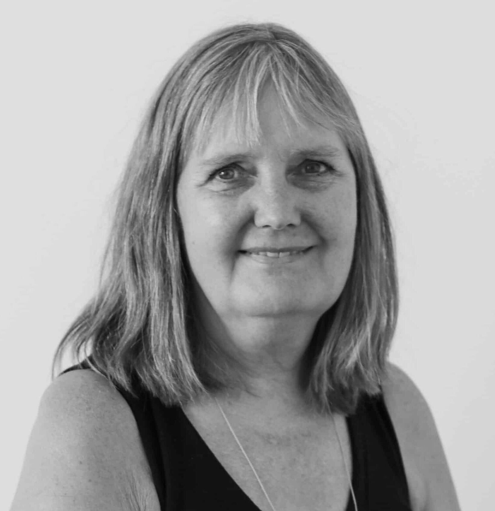 Portræt af kvinde med skulderlangt hår og sort top, fotograferet mod en lys baggrund.