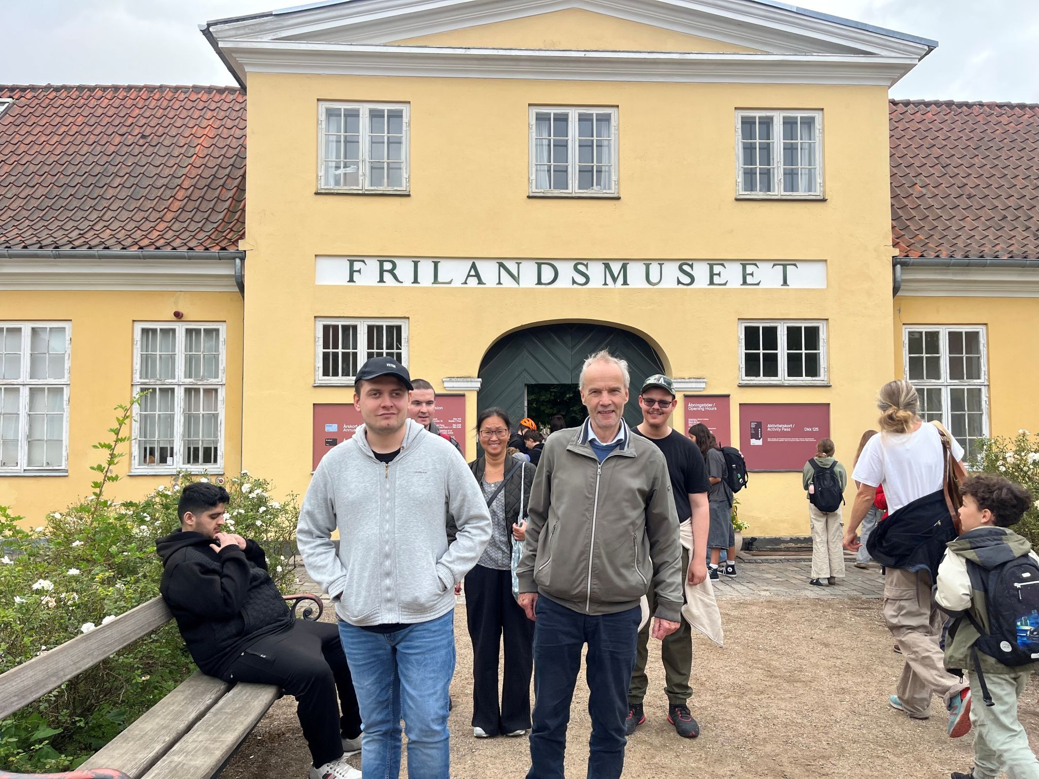 En gruppe fra Center for Autisme står foran indgangen til Frilandsmuseet i Kongens Lyngby. Deltagerne smiler og gør sig klar til en fælles udflugt.