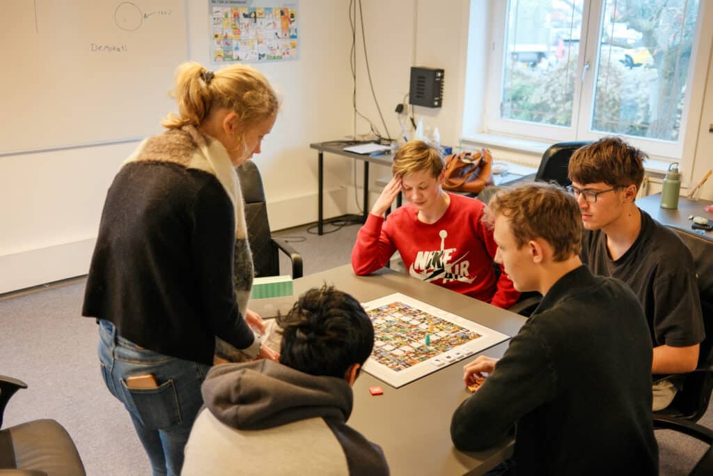 Elever og lærer arbejder sammen om læringsspil som eksempel på autismepædagogik i skolen og inkluderende undervisning.